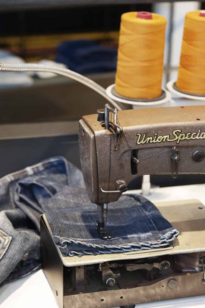 Nudie Jeans a pair on a sewing machine being fixed